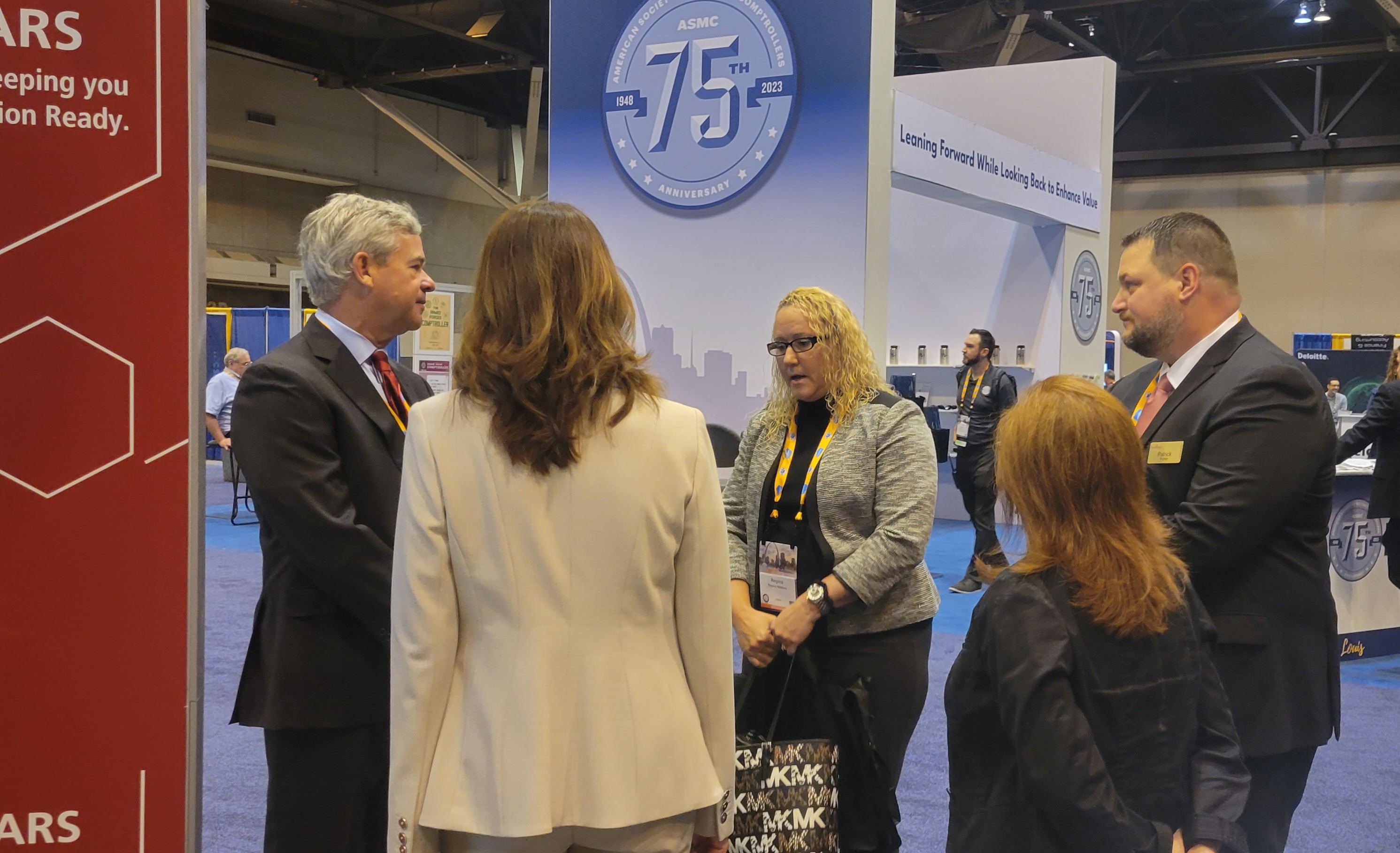 Group of professionals talking in a circle at the Management Concepts booth in the exhibit hall