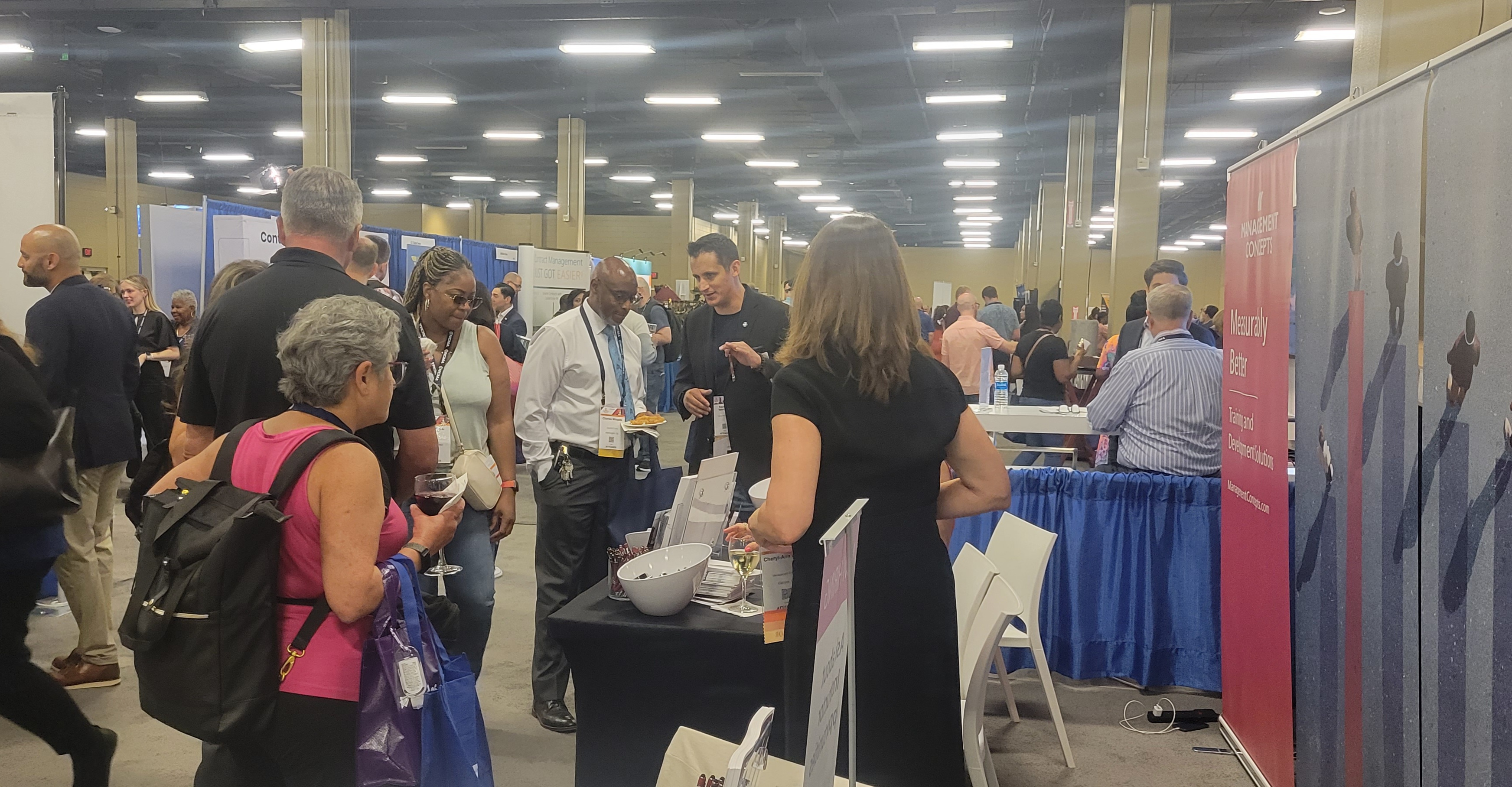 A crowd of people talking and visiting vendor booths in exhibit hall